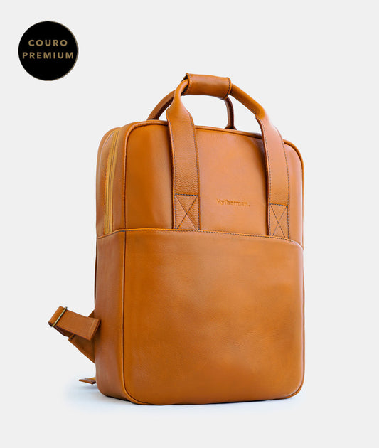 Mochila de couro legítimo em cor caramelo safari da marca Hylberman Acessórios, ideal para executivos. Imagem sobre fundo branco destacando a elegância e praticidade. Perfeita para carregar na mão, garantindo estilo e funcionalidade em todas as ocasiões. Adquira já a sua!